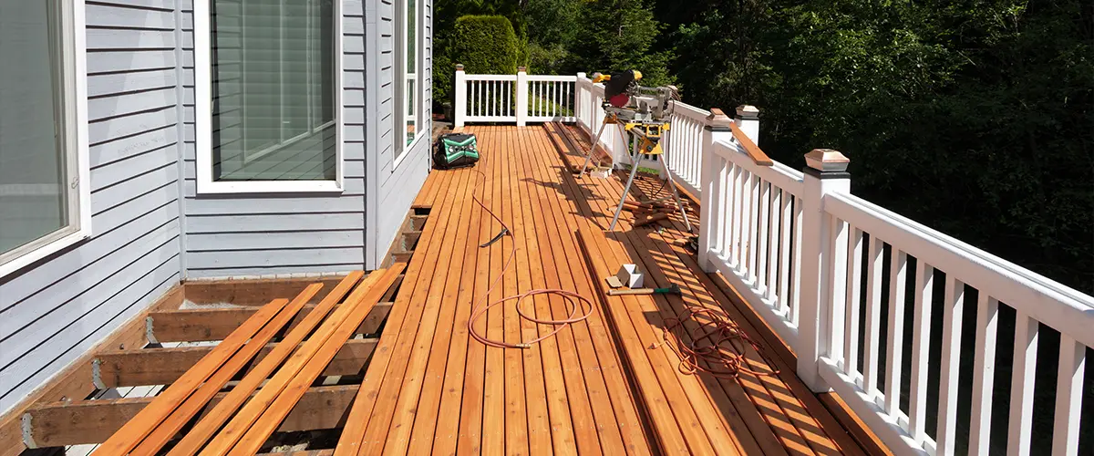 Cedar decking being installed on a deck with white railings