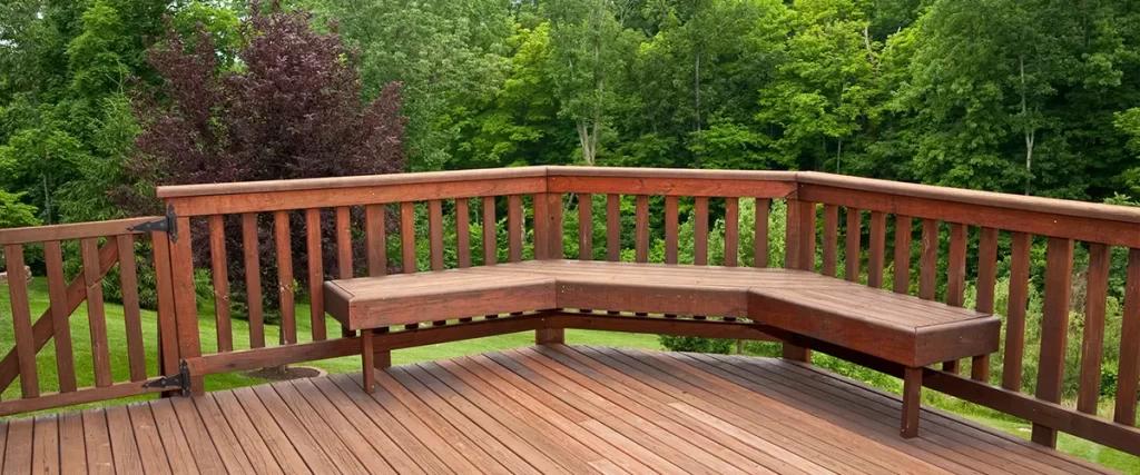 A drinking rail on a wood deck with a bench