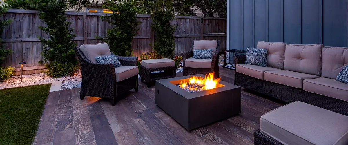 A lit fireplace on a deck with chairs and benches