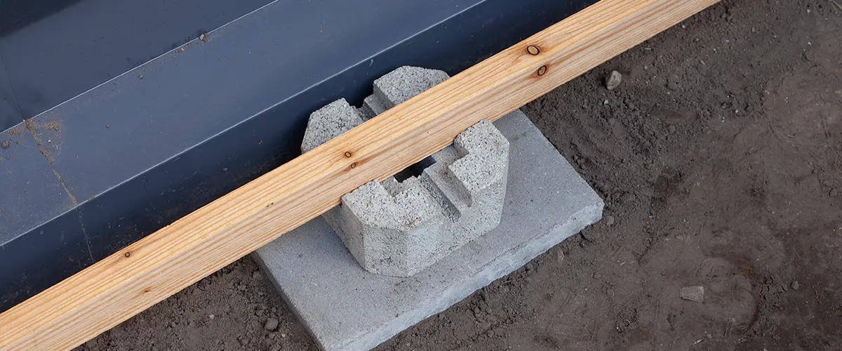 A metal frame with a piece of wood and a concrete block for a deck