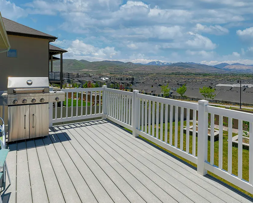 Composite deck with grill area, white LVP railing, and gray composite boards
