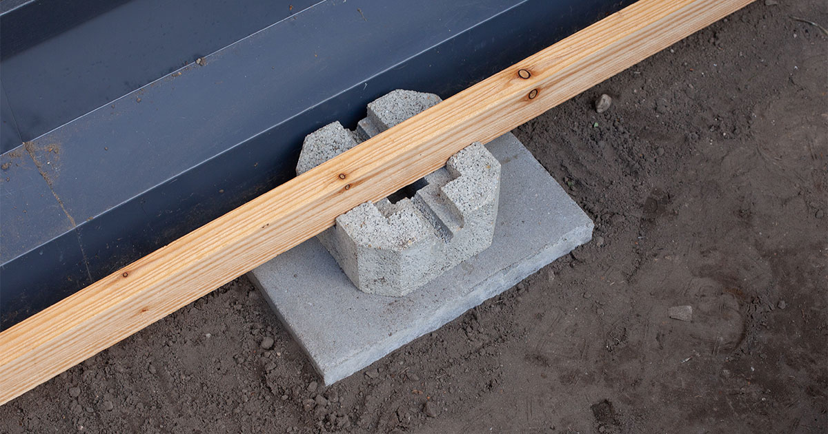 A concrete deck block and a piece of lumber for a deck construction