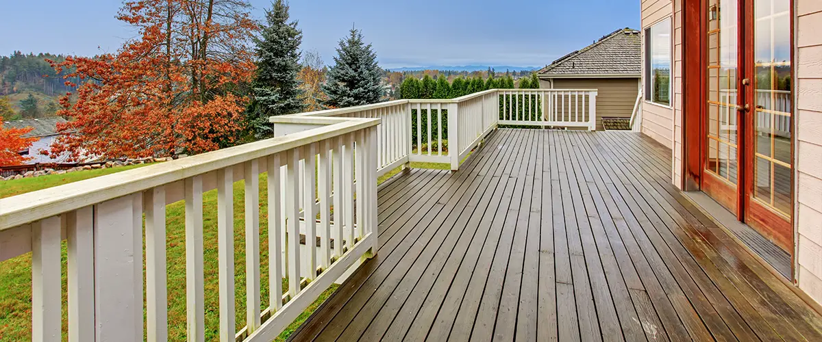 The deck building cost for an elevated wood deck with white railings after rain