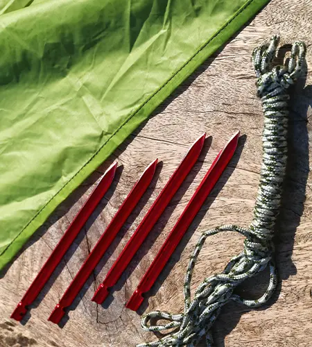 Red ground spikes with a rope and a green tarp