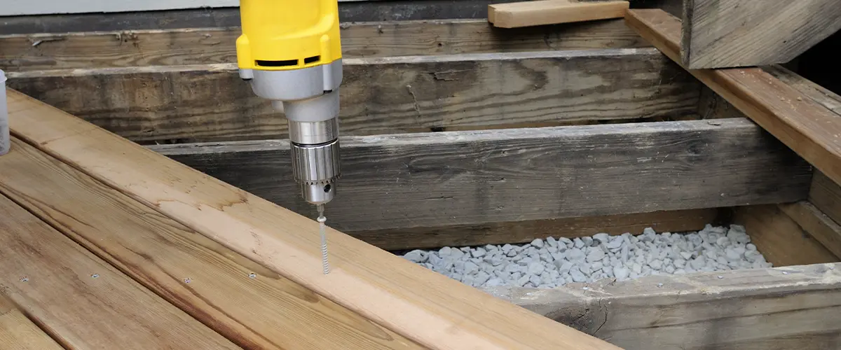 A yellow screw driver on wood decking boards