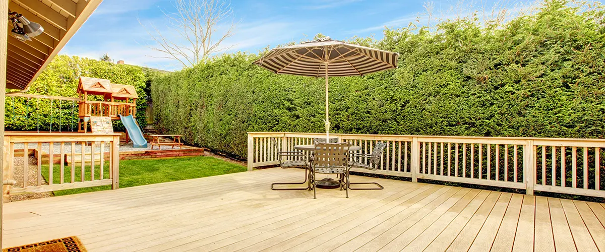Composite decking in a backyard with an umbrella and a large patch of grass