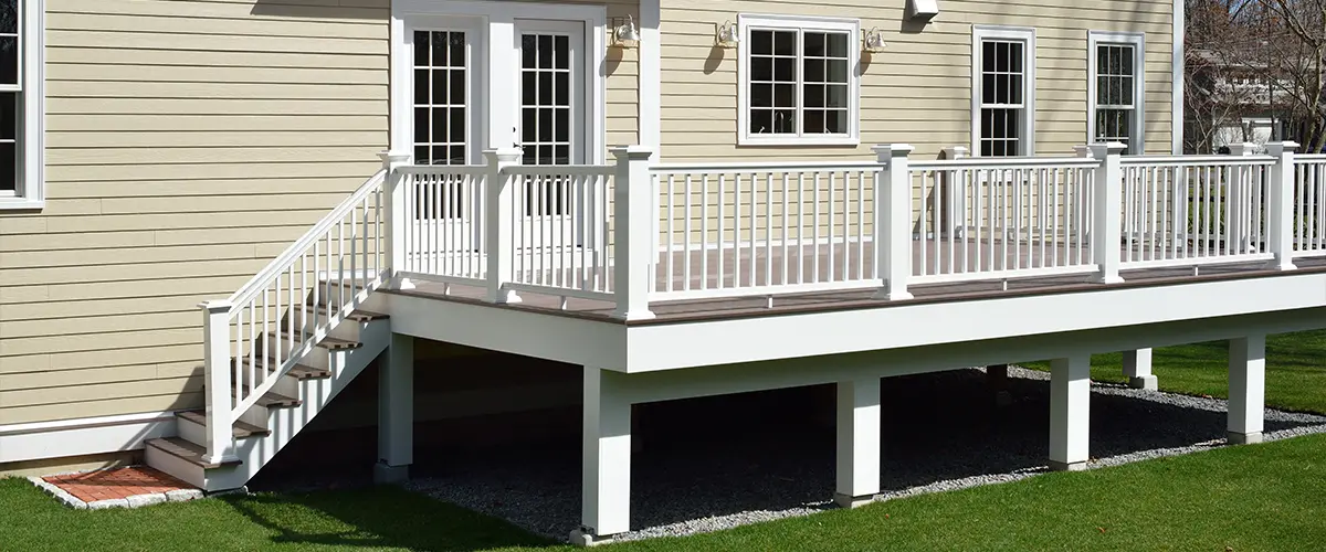 Deck posts with white railing on a beige home