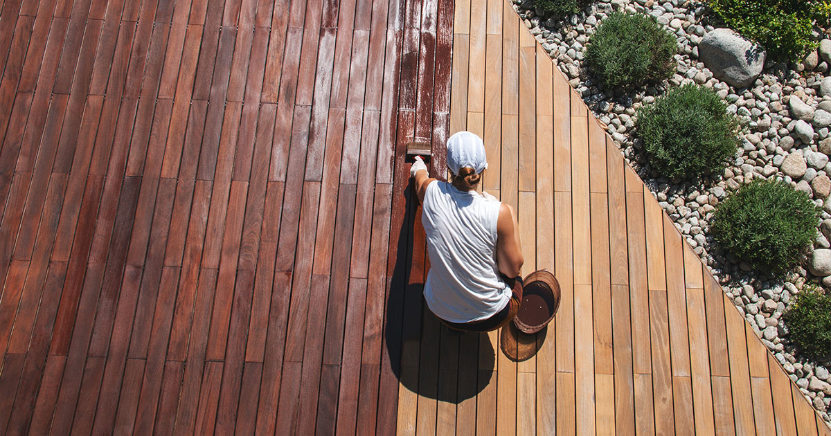 Worker staining a wooden deck.