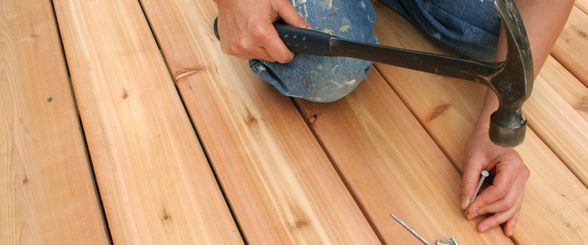 Man-repairing-a-wood-deck-with-hammer-and-nails