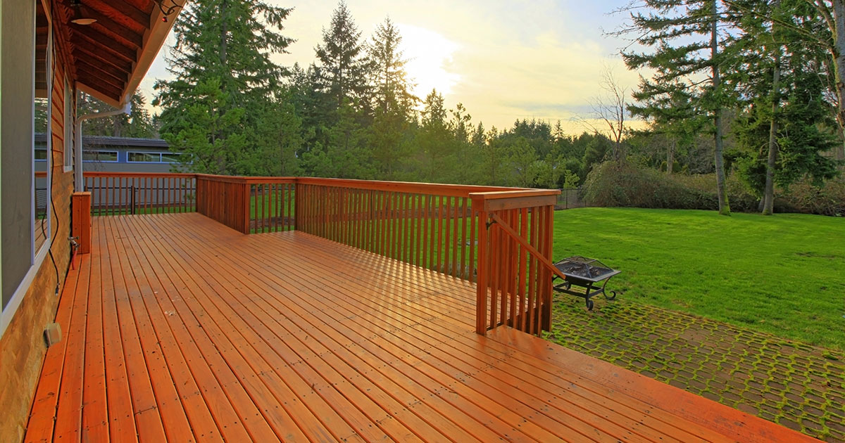 Freshly stained wooden deck in Annapolis, with railing, surrounded by lush greenery, perfect for outdoor relaxation and entertaining