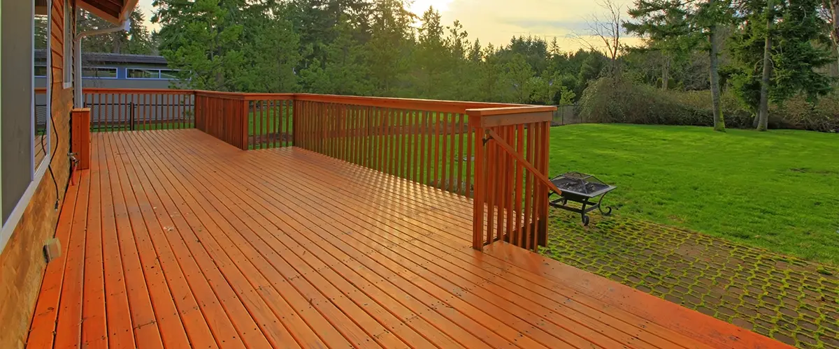 Freshly stained wooden deck in Annapolis, with railing, surrounded by lush greenery, perfect for outdoor relaxation and entertaining