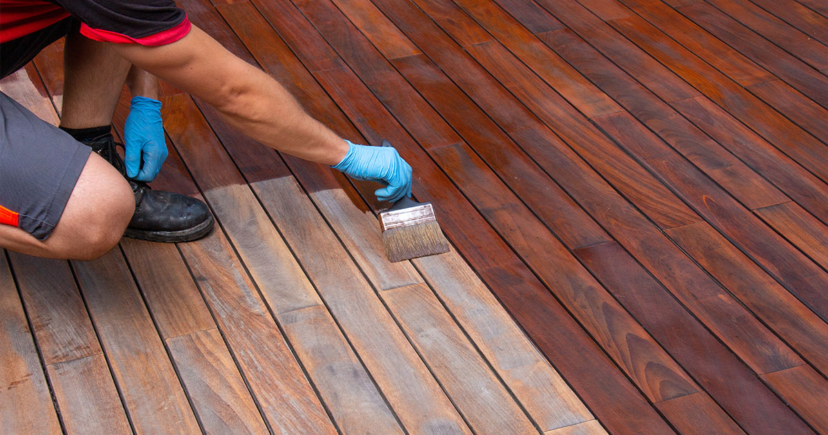 Professional deck staining with a paintbrush.