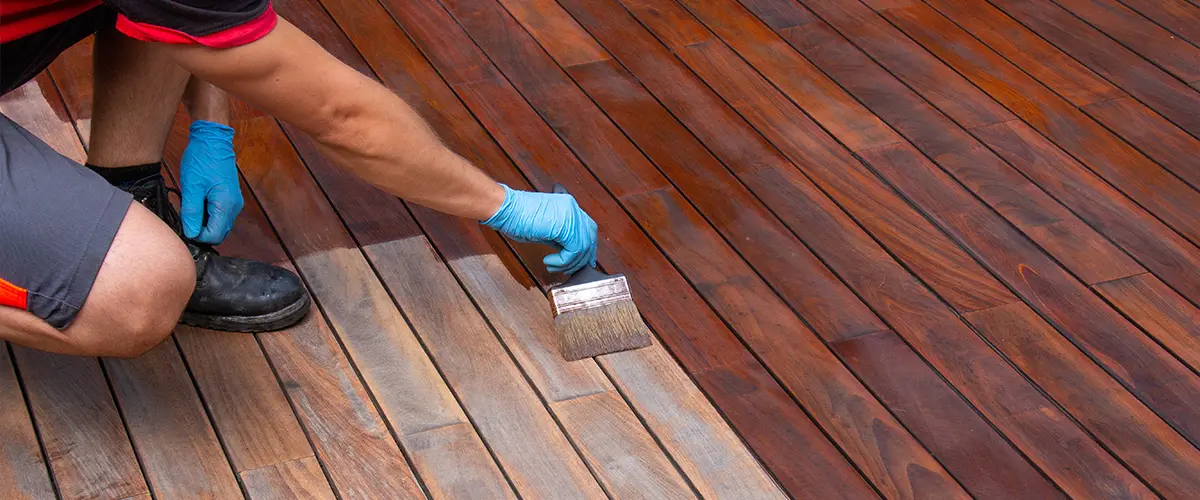 Professional deck staining with a paintbrush.