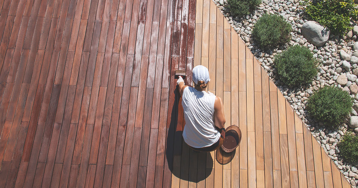 Professional-applying-stain-to-a-wooden-deck,-restoring-and-protecting-outdoor-wood-surfaces-for-longevity-and-beauty.