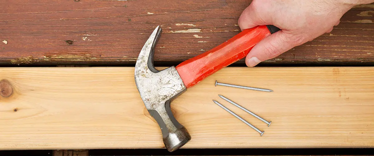 Close-up of hammer and nails used for wooden deck board repair